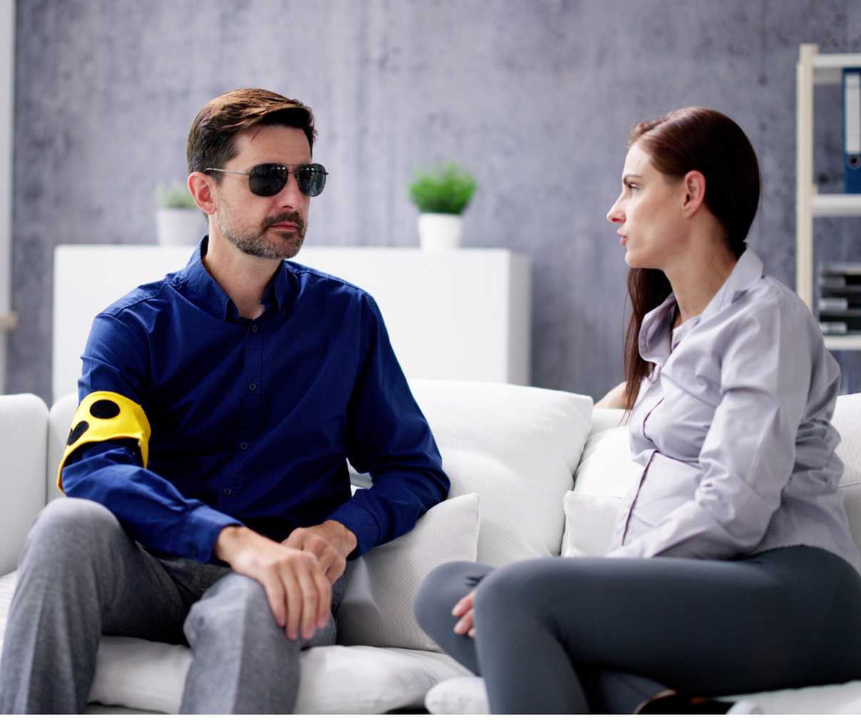 A man with vision loss sat next to a woman on a sofa