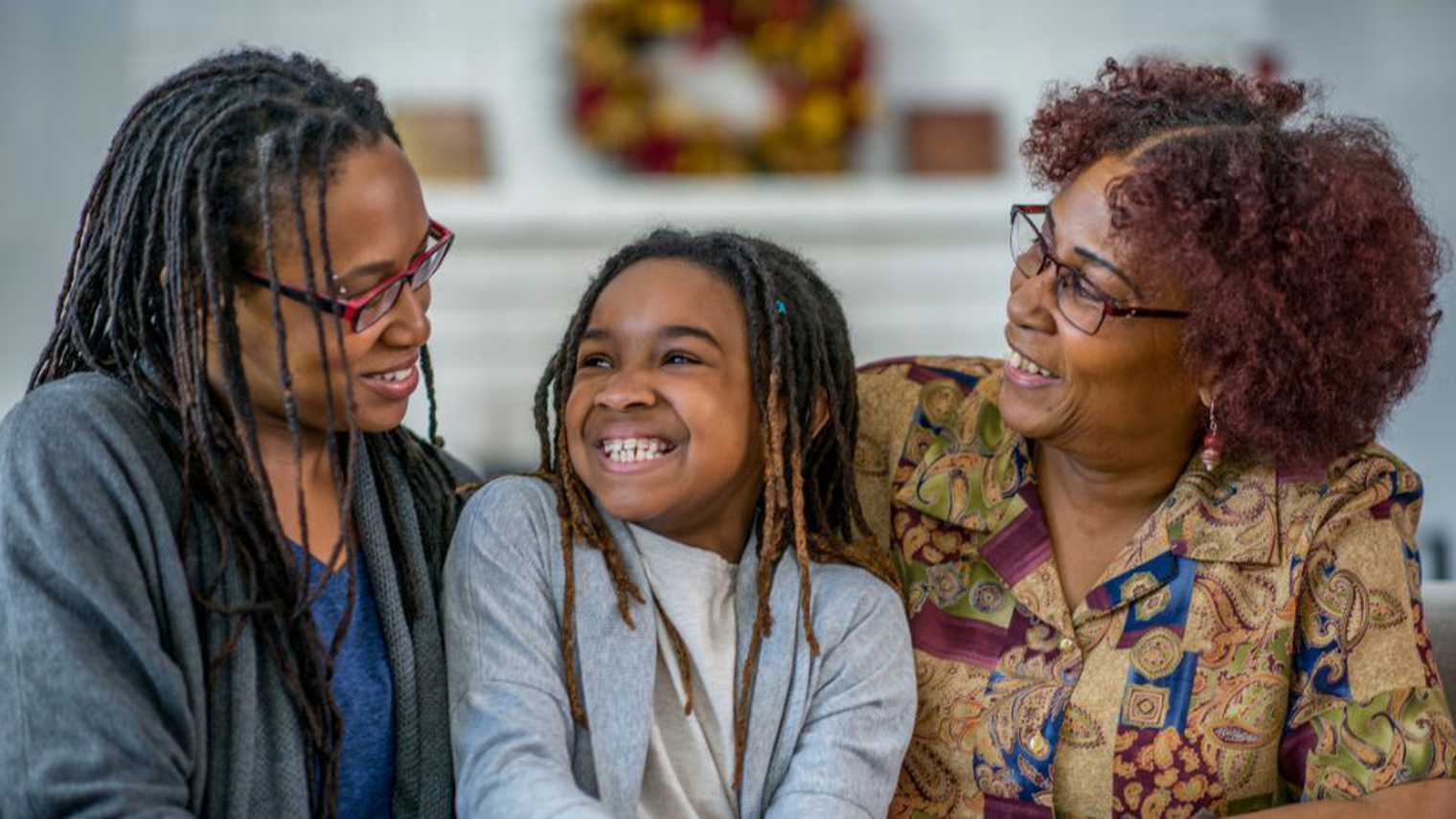 Two women wearing glasses smiling down at young girl